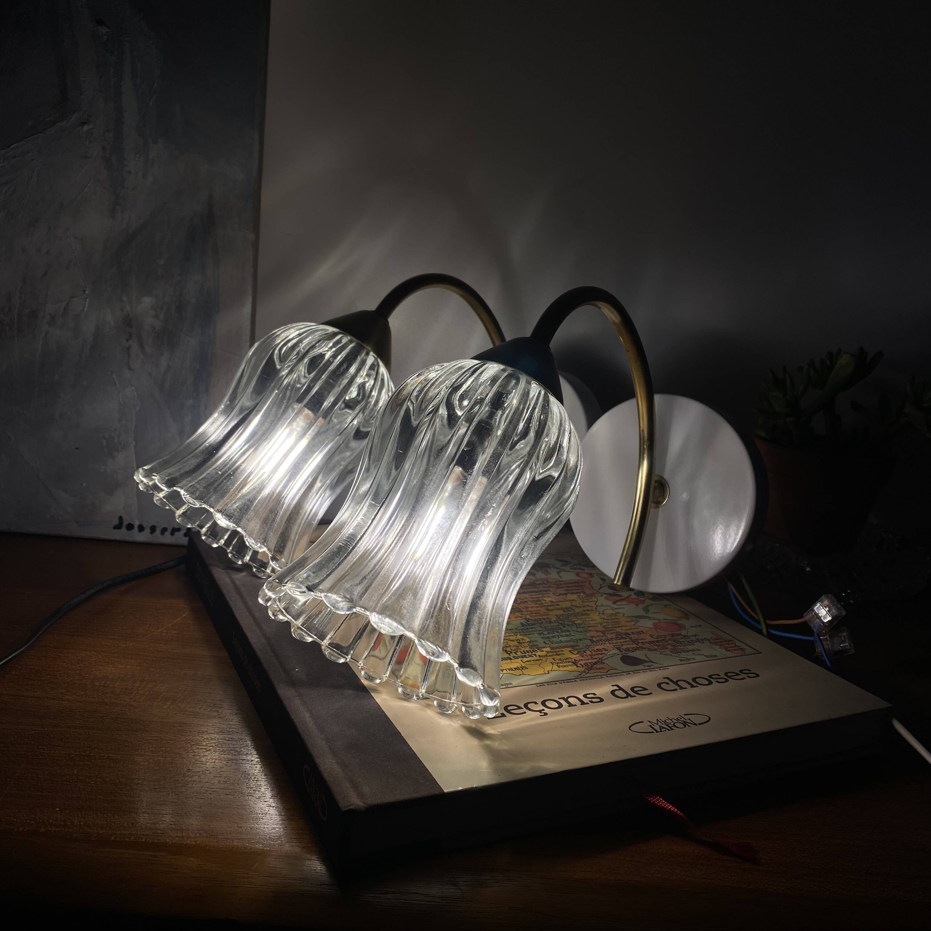 Pair of wall sconces in brass with transparent tulip glass shade.