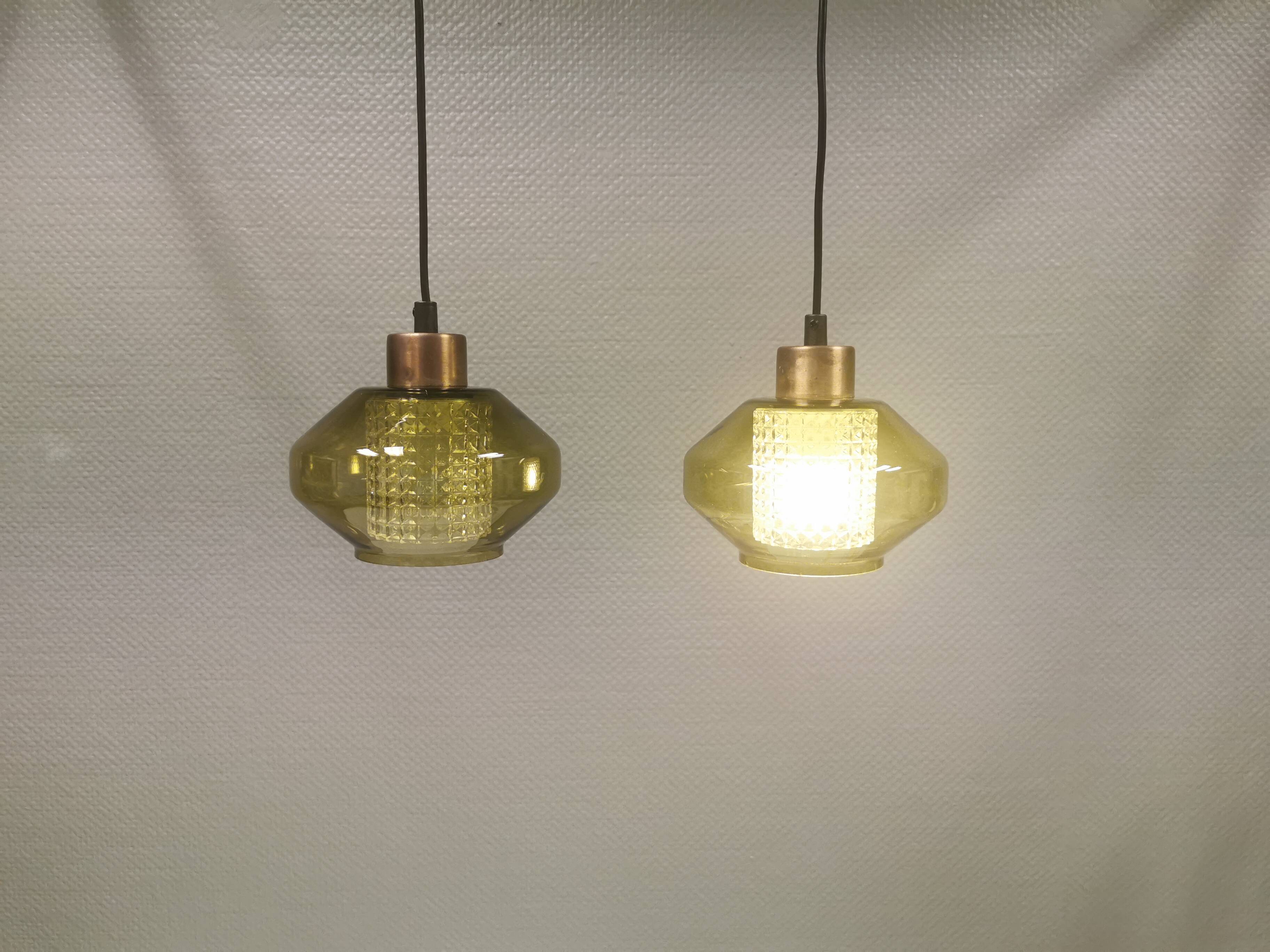 Hanging lamp with an outer shade of olive green glass and an inner shade of clear, crystal glass.