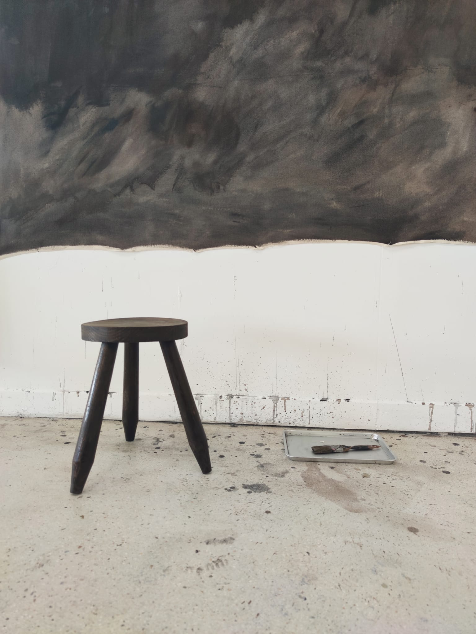 Small brutalistic tripod stool in dark wood tapered feet circular seat
