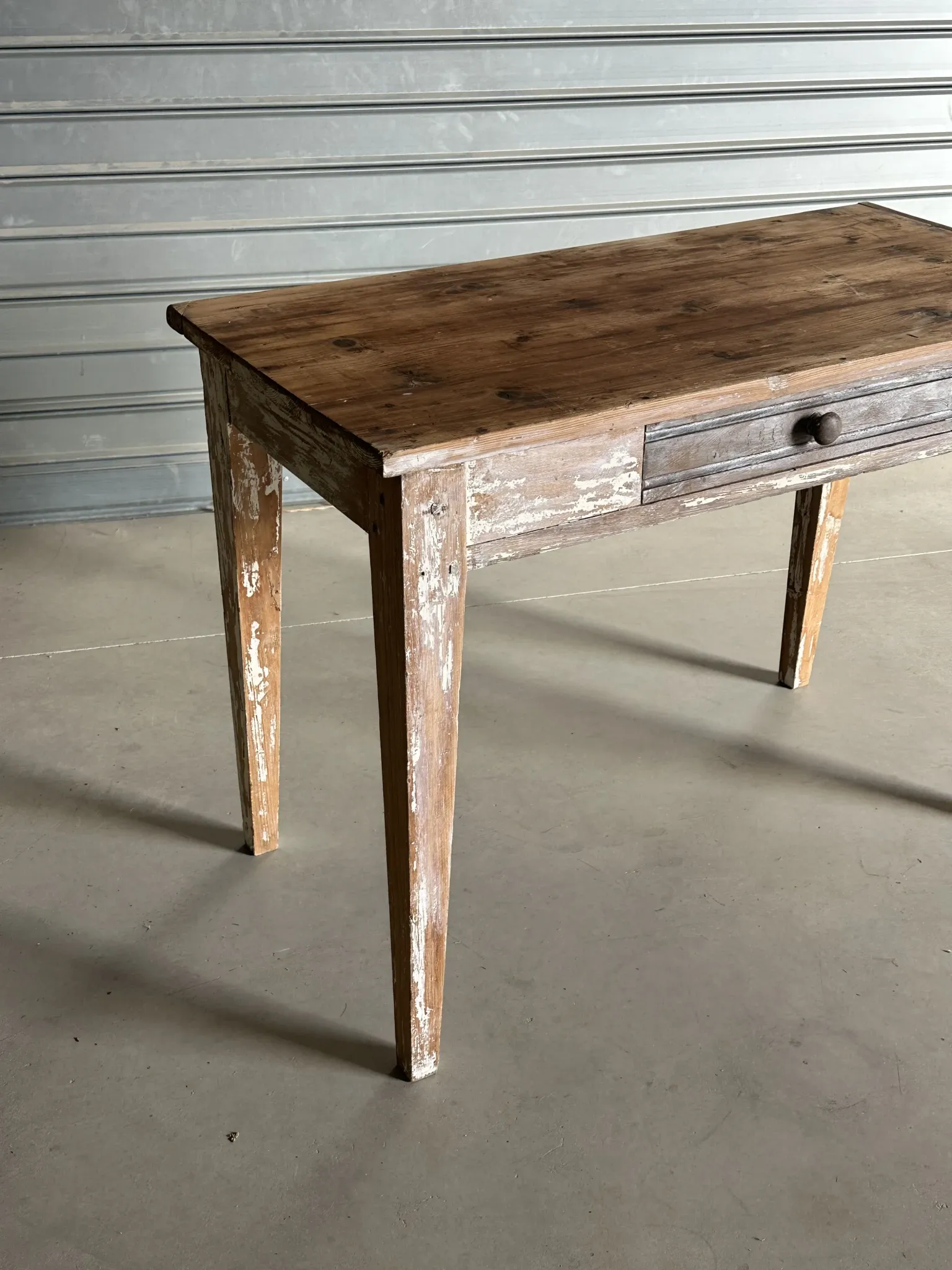 Vintage table made of raw wood with a distressed white base.