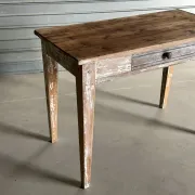 Vintage table made of raw wood with a distressed white base.