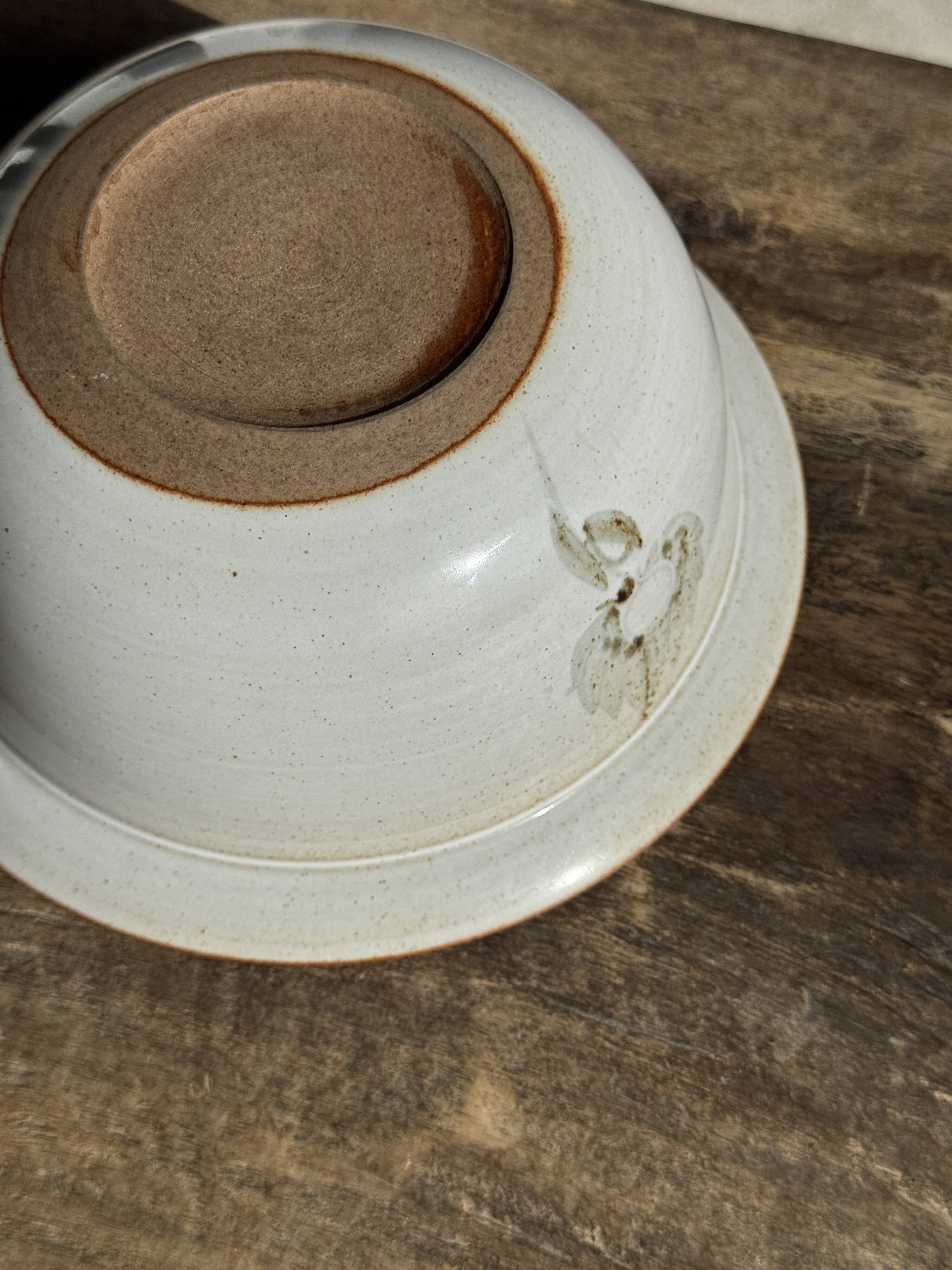 Small thick stoneware bowl with a stylised flower pattern in white on the outside, b