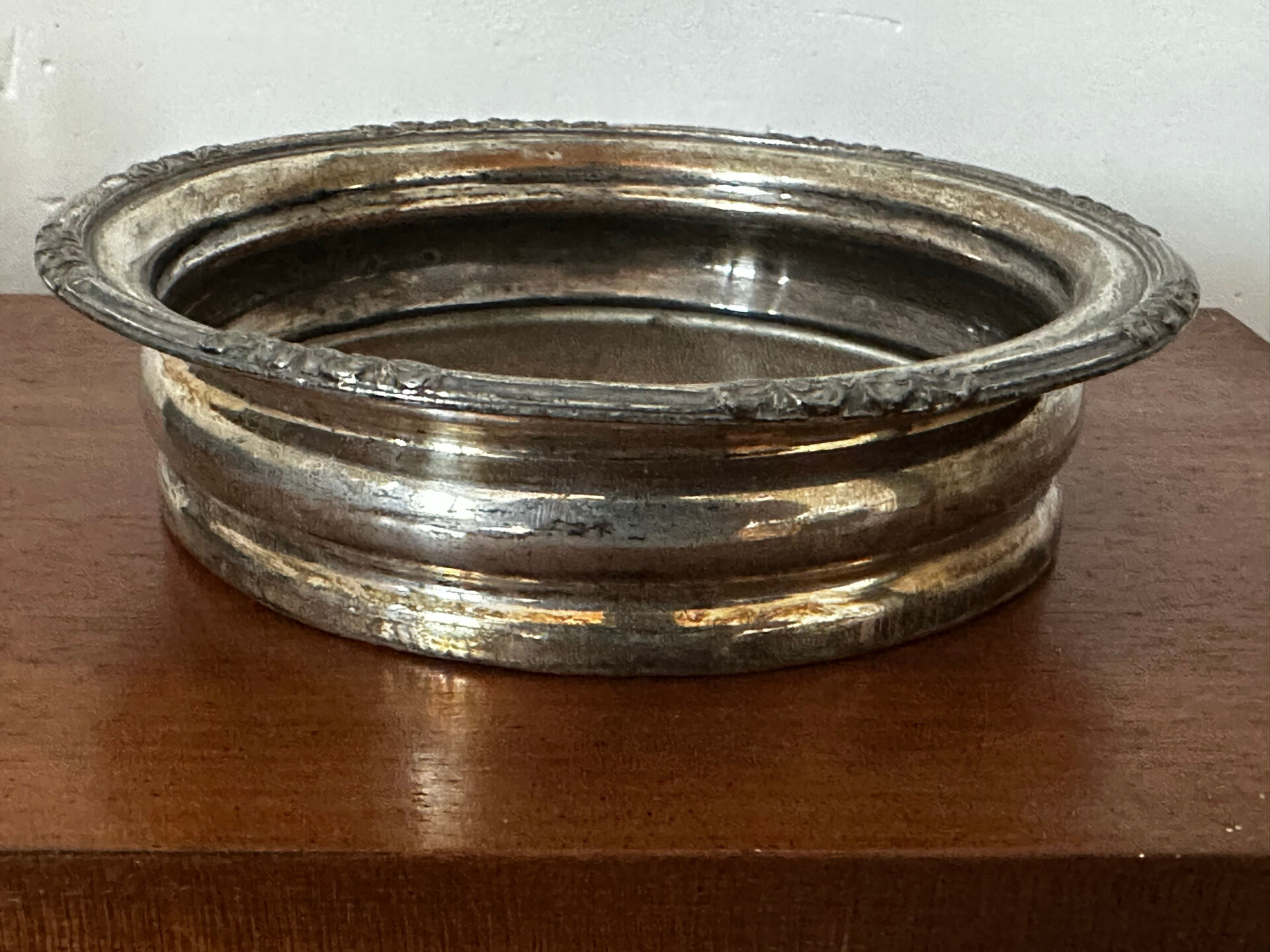 Antique silver-plated bottle coaster with floral decoration.