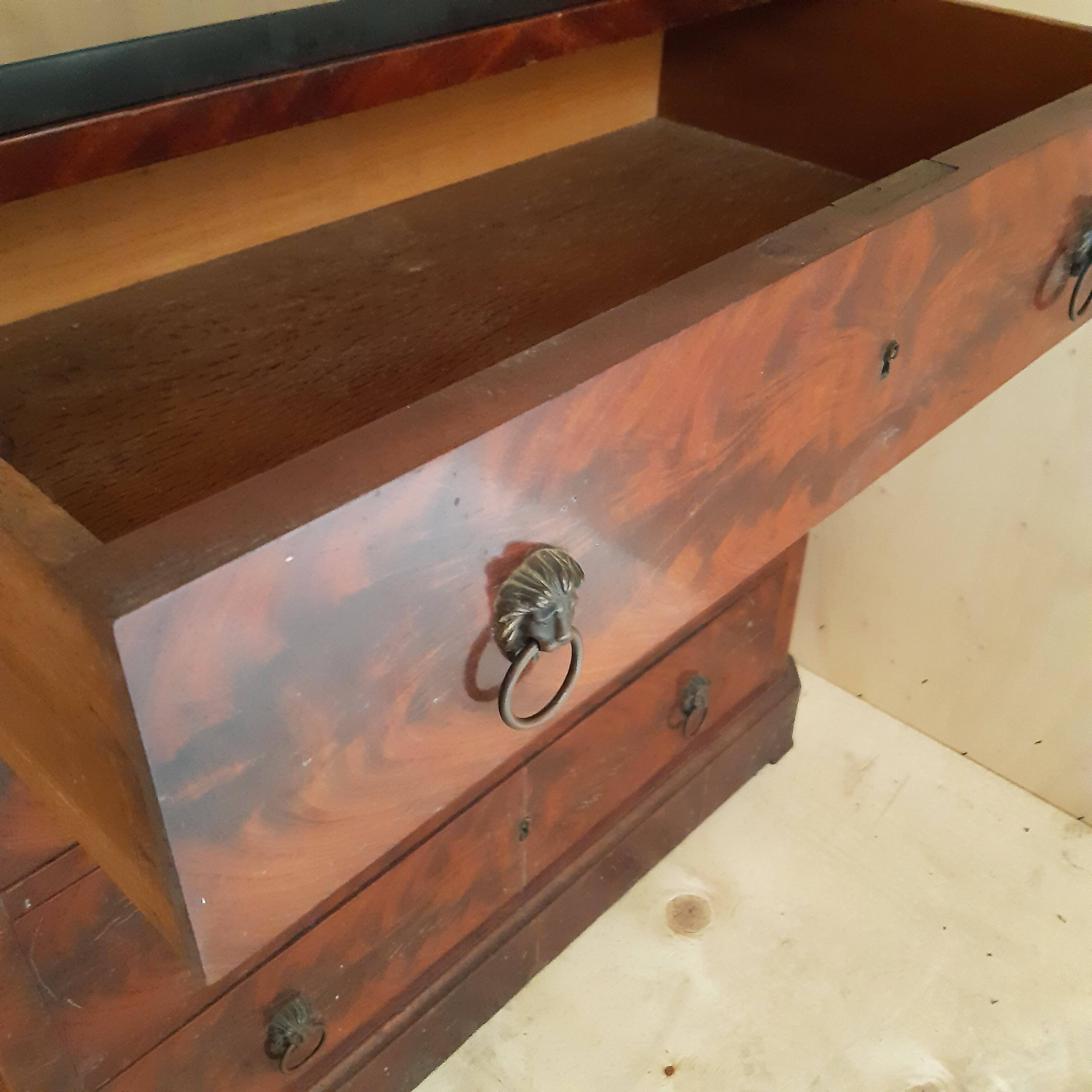 Antique chest of drawers with mahogany veneer and lion heads