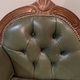 Antique carved wooden bench with green upholstered seat and backrest.