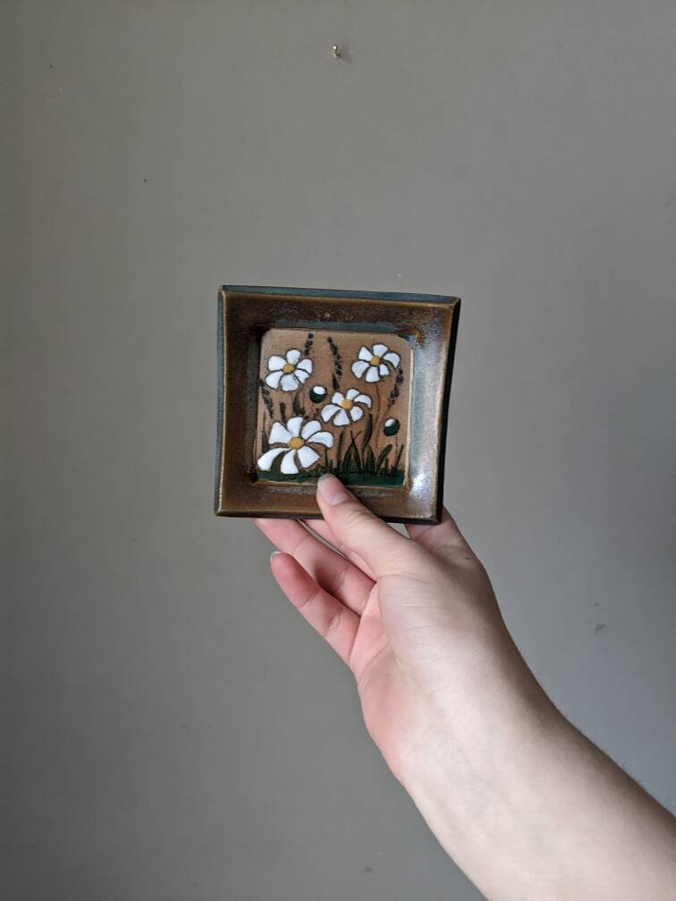 Handcrafted ceramic wall hanging with floral daisy decoration