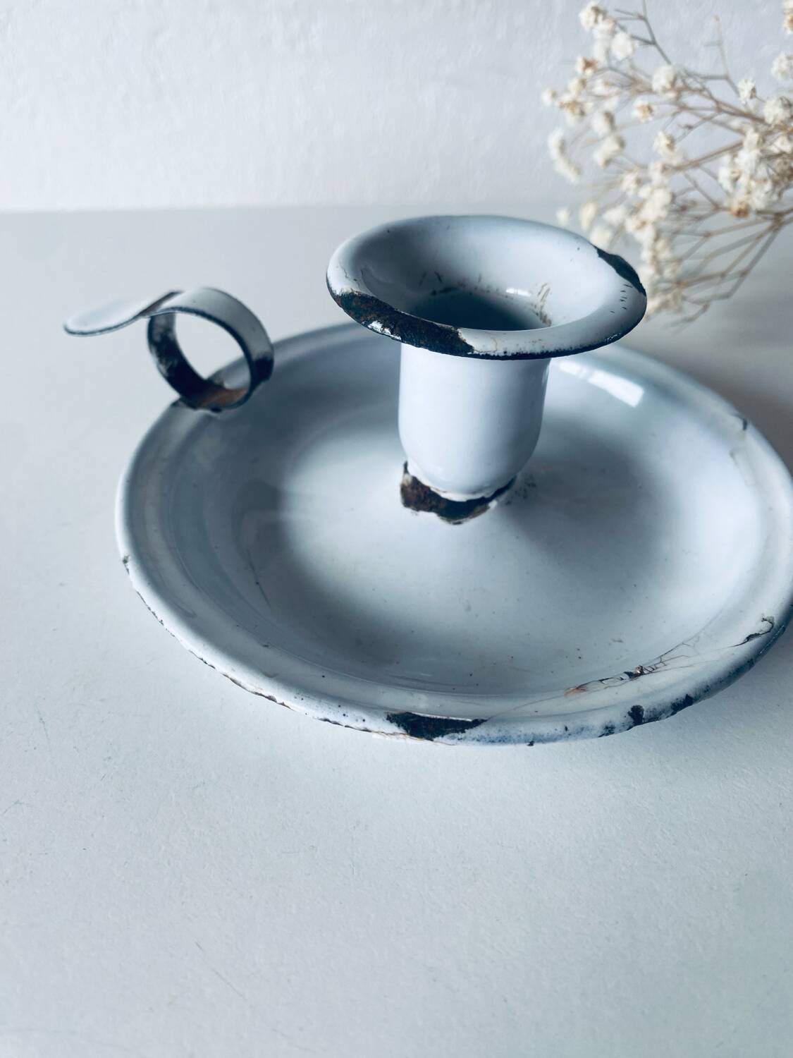 Old candle holder in white enameled metal