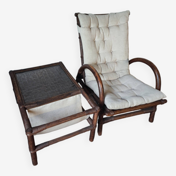 Relaxed armchair in bamboo and rattan with its small side table. Beige linen cushion.