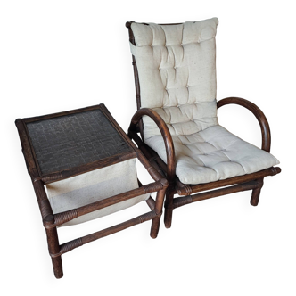 Relaxed armchair in bamboo and rattan with its small side table. Beige linen cushion.