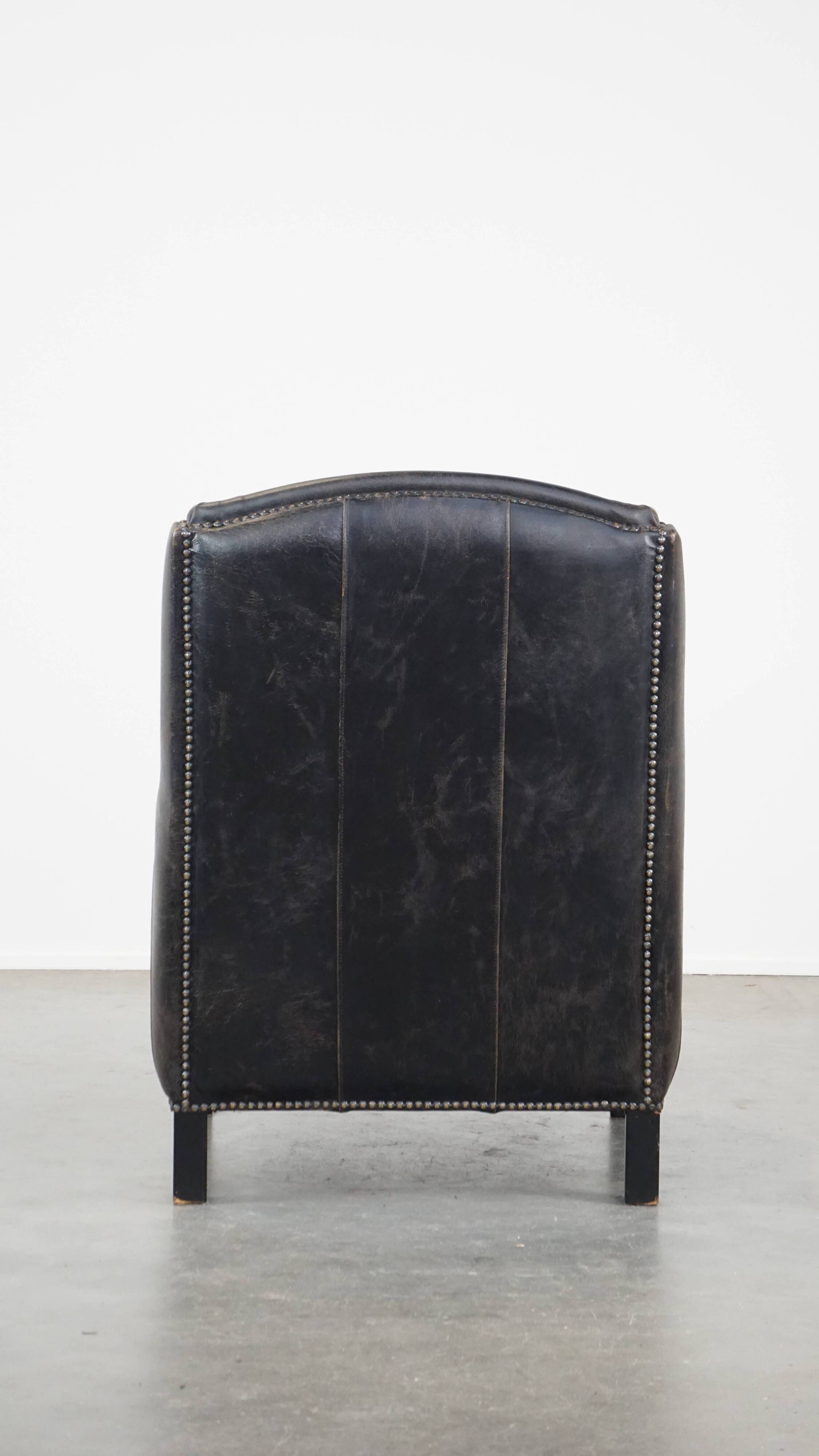 Black cow leather armchair in industrial style finished with decorative nails