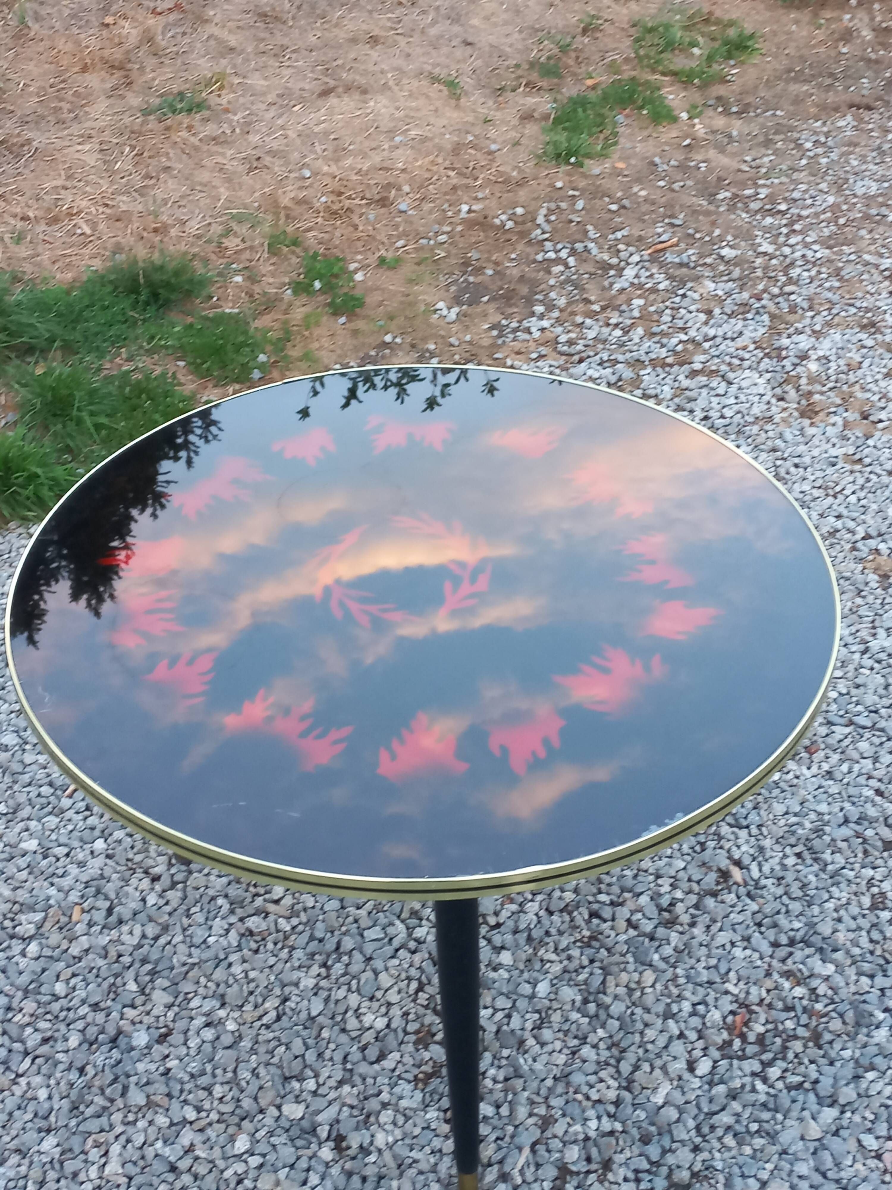 Vintage coffee table with glass top and tripod legs in blackened wood from the 1960s.