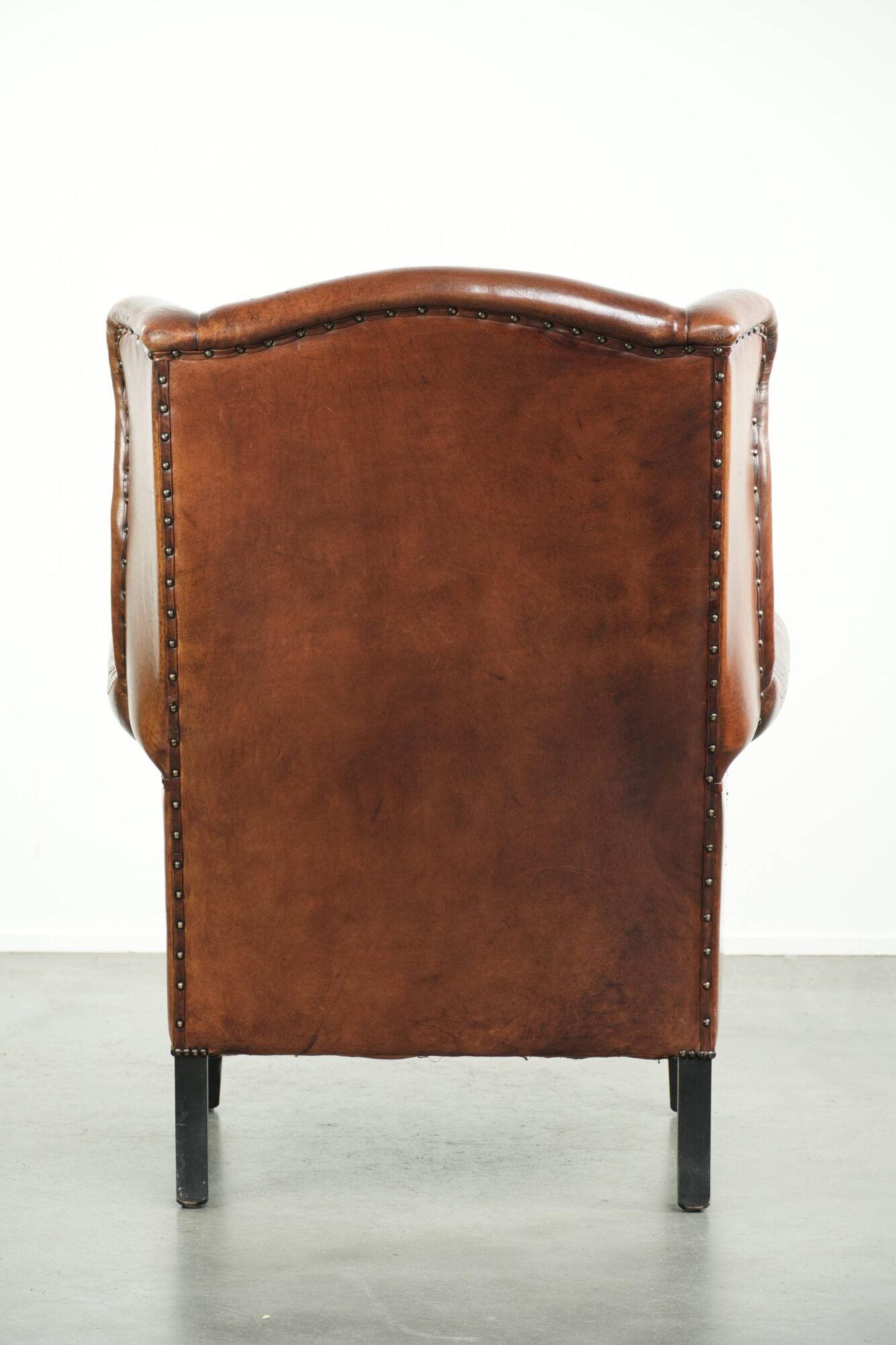 Sheepskin wingback armchair finished with black piping and a correct seat