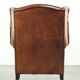 Sheepskin wingback armchair finished with black piping and a correct seat