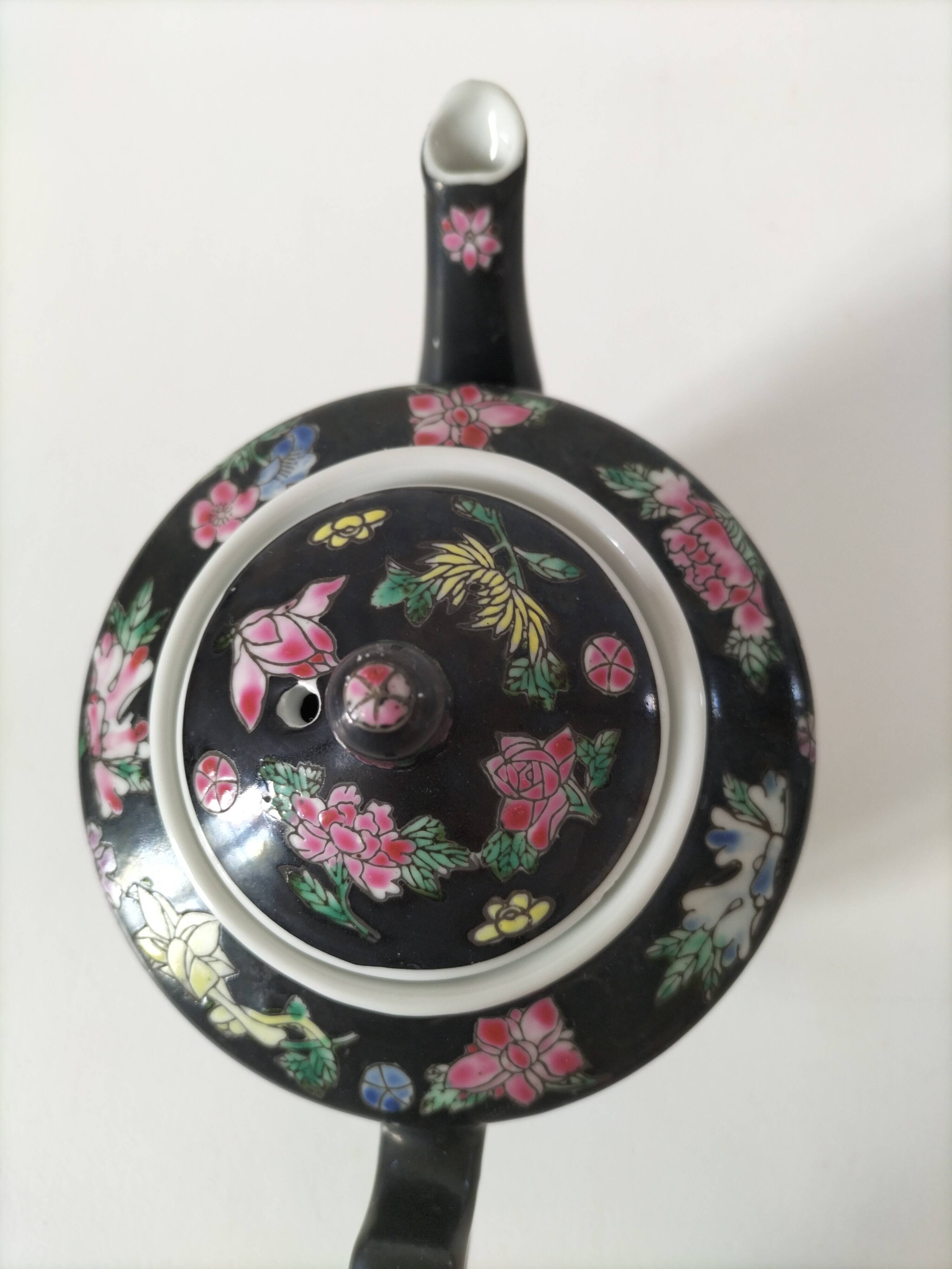 Vintage Chinese teapot with floral polychrome decoration on a black background.