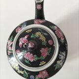 Vintage Chinese teapot with floral polychrome decoration on a black background.