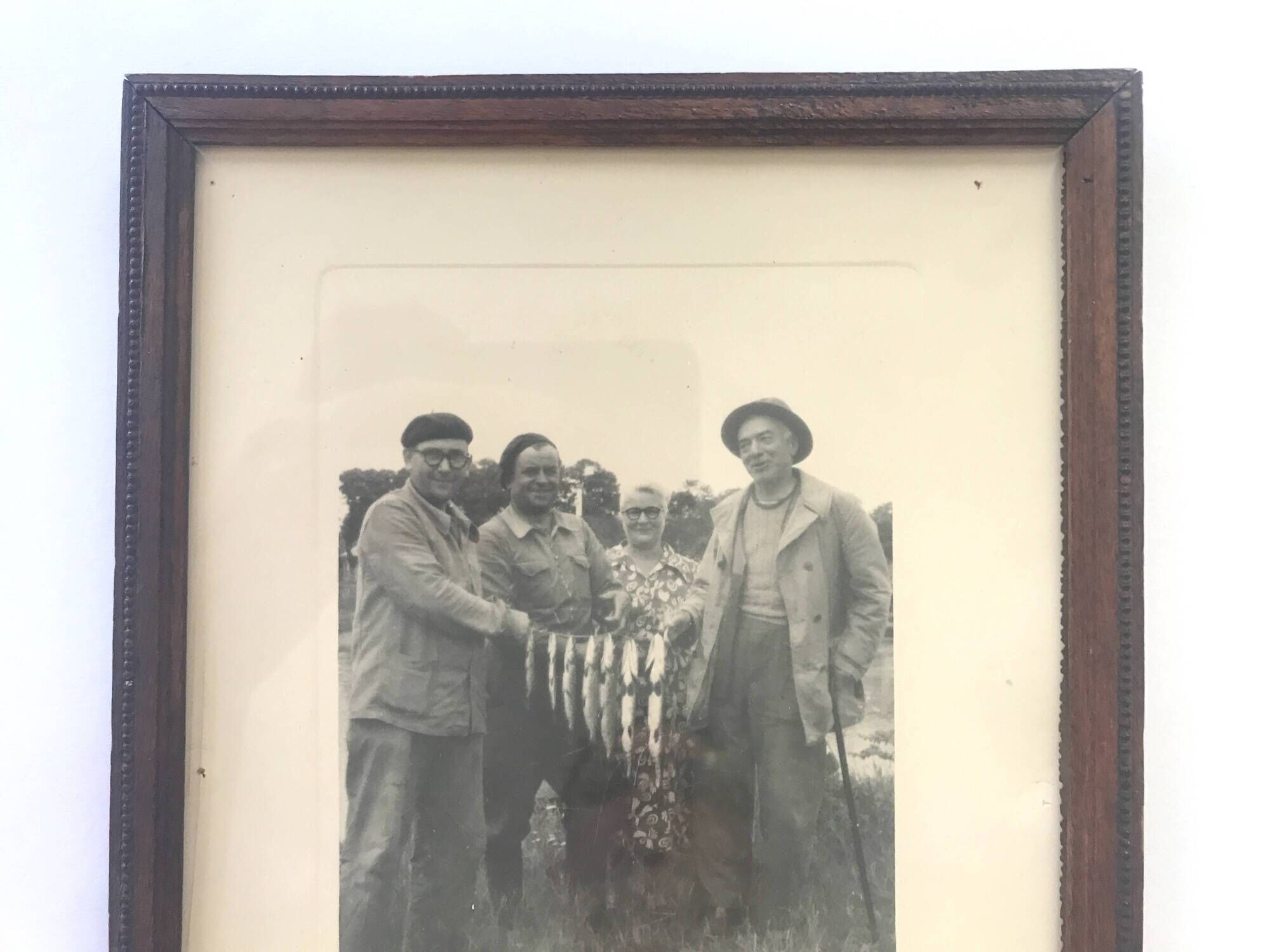 Fishing trophy with radiant faces, c. 1950. Black and white photograph.