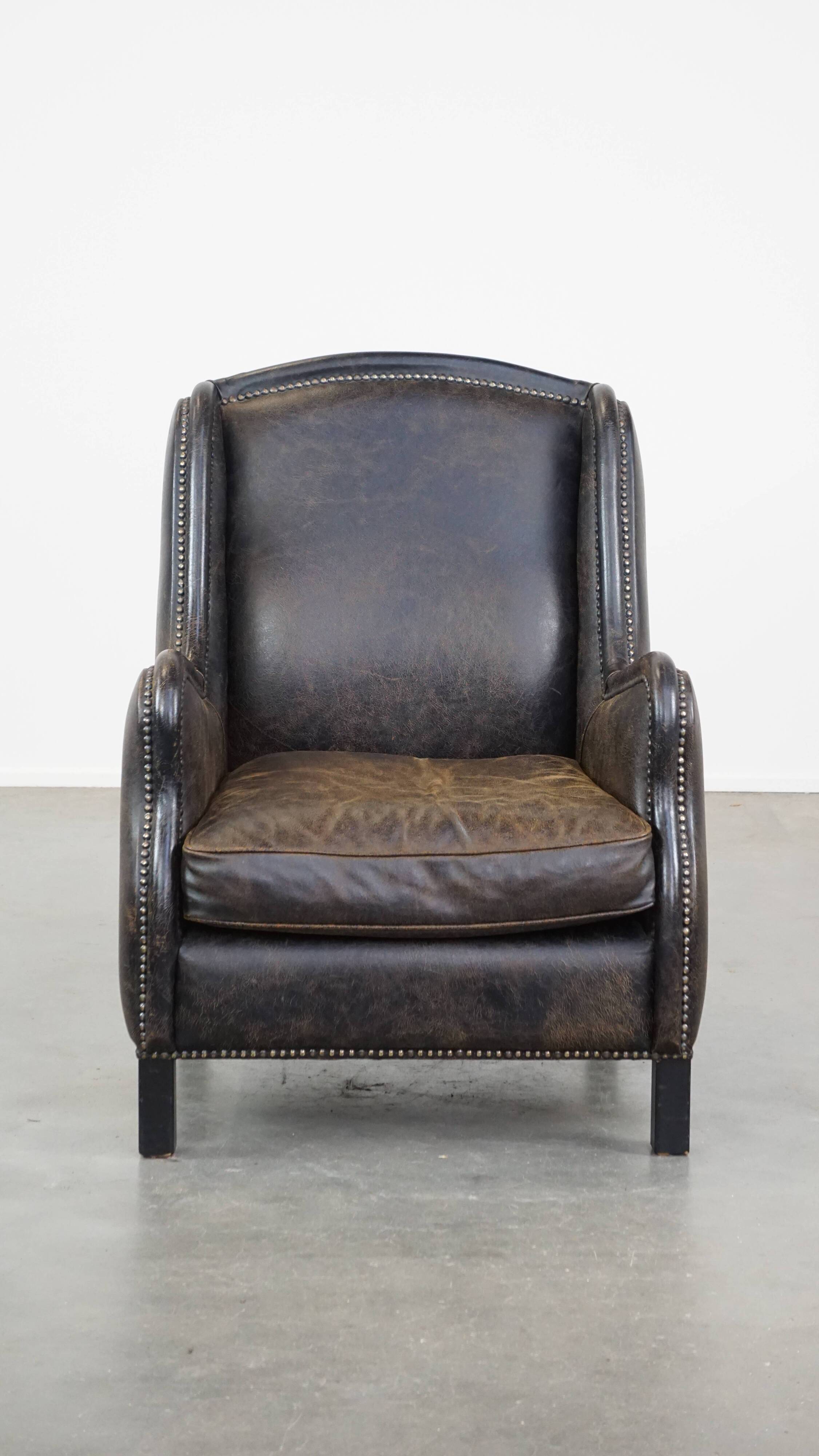 Black cow leather armchair finished with decorative nails, industrial style