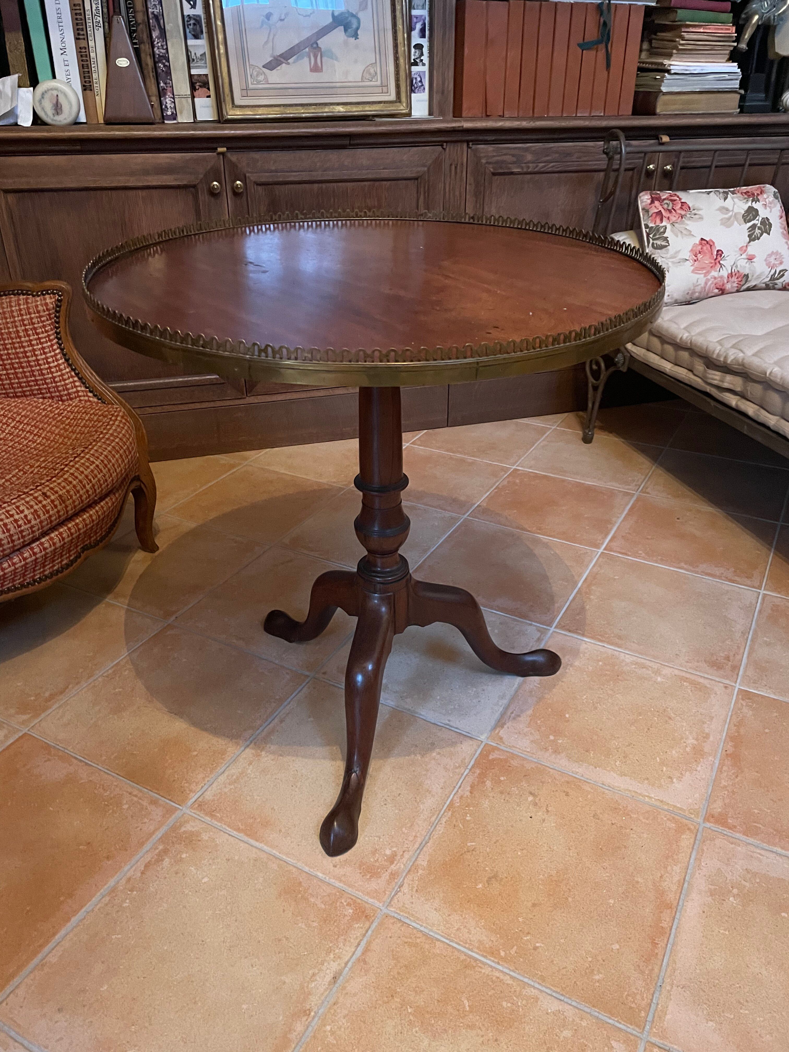 Foldable tripod side table in carved mahogany with brass trim.