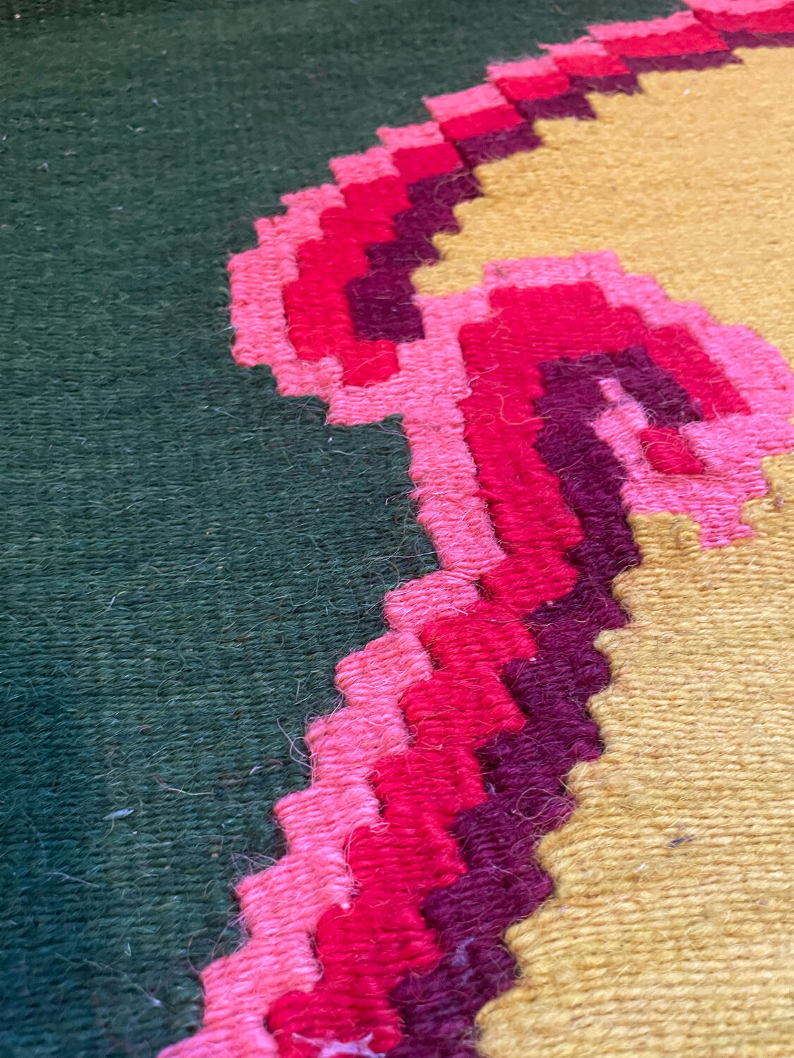 Vintage wool rug with pink flowers on green and yellow background made by hand in Transylvania