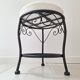 Black iron stool/pouf with its boucle fabric cushion.