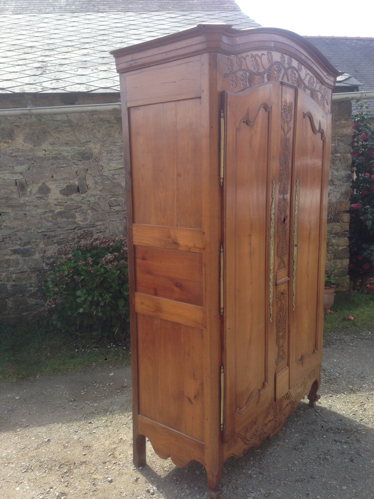 Armoire Louis XV Nantaise sculptée à grappes de raisin, chapeau de gendarme en cerisier fin 19eme.