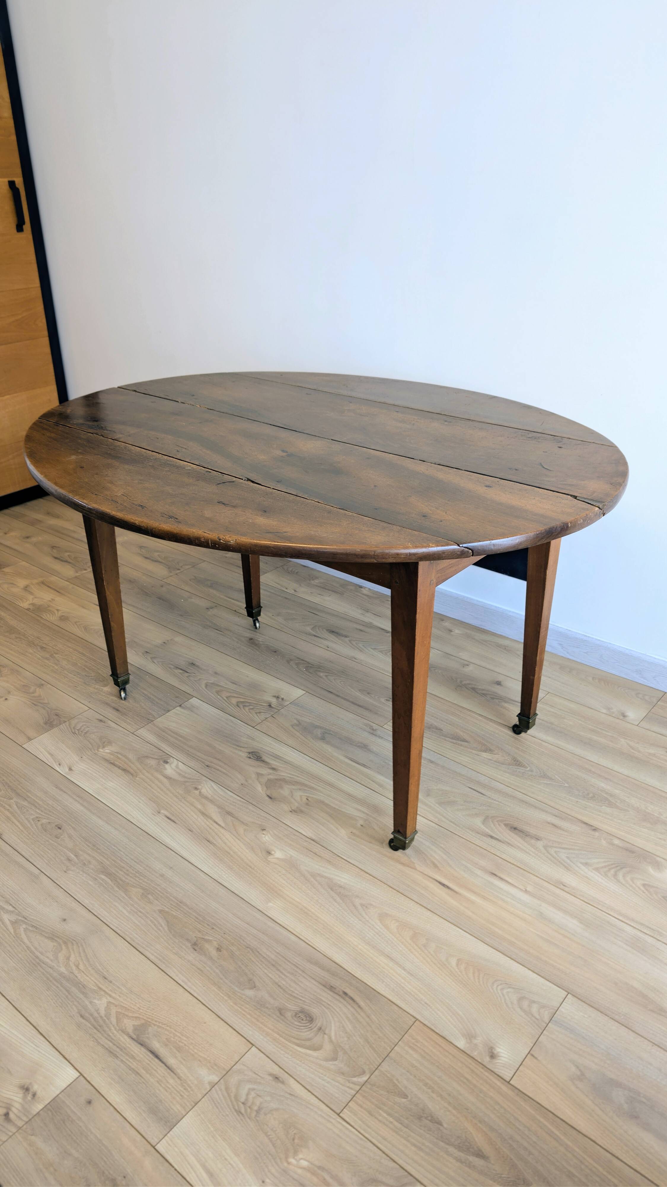 Antique wooden folding table with a patina and brass wheels.