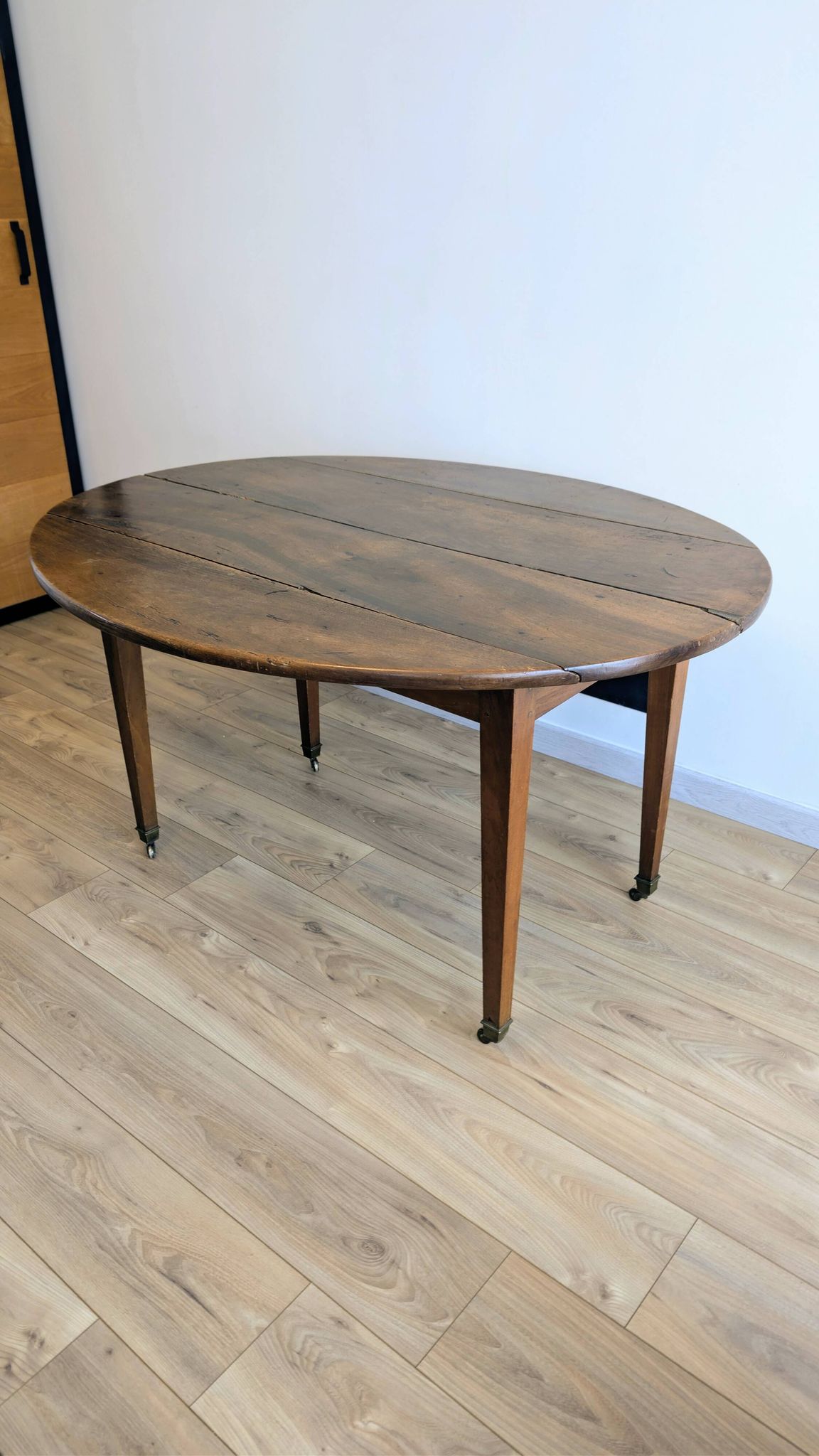 Antique wooden folding table with a patina and brass wheels.