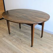Antique wooden folding table with a patina and brass wheels.