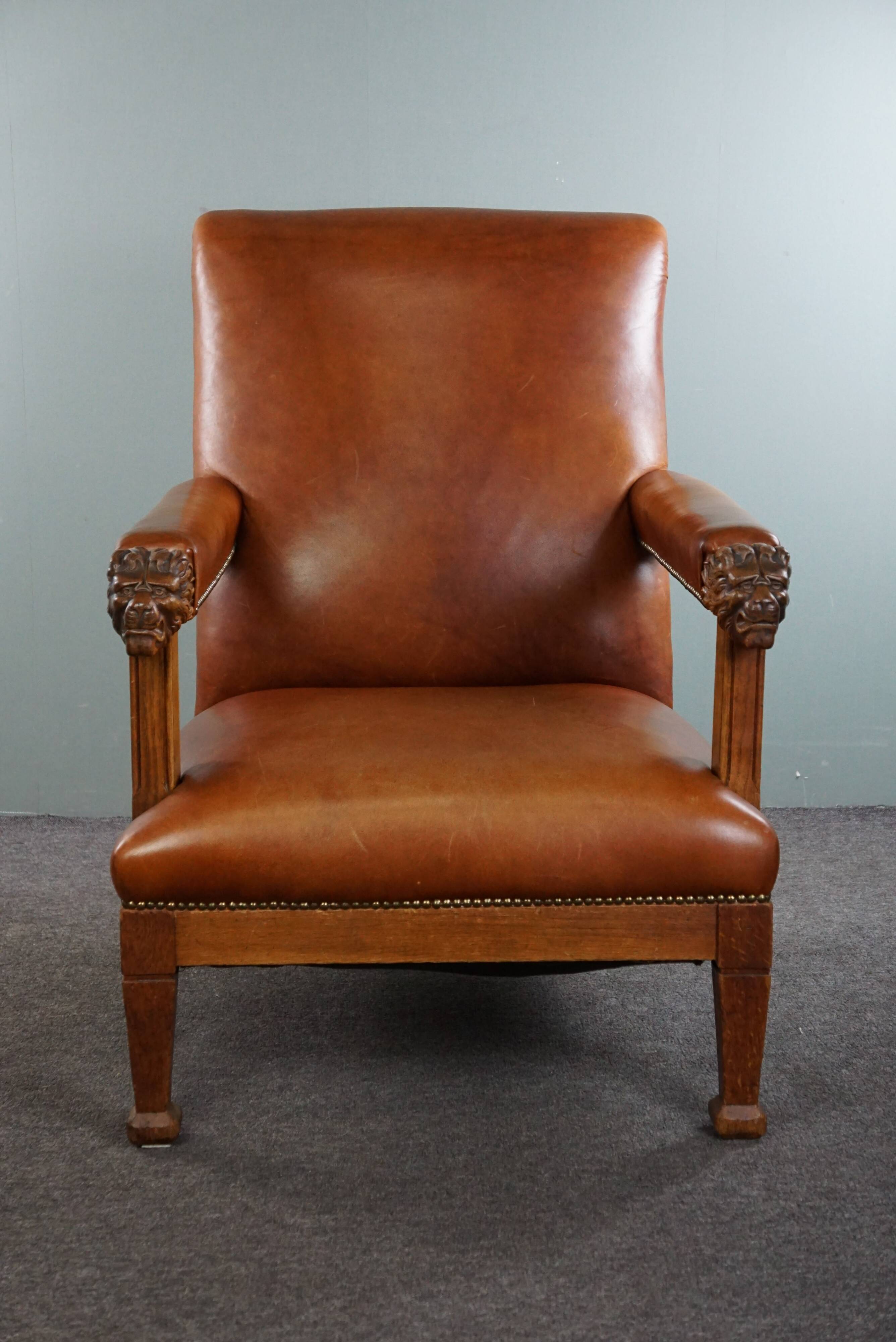 Armchair with lion heads reupholstered in cognac-colored cowhide leather