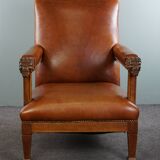 Armchair with lion heads reupholstered in cognac-colored cowhide