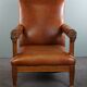 Armchair with lion heads reupholstered in cognac-colored cowhide leather