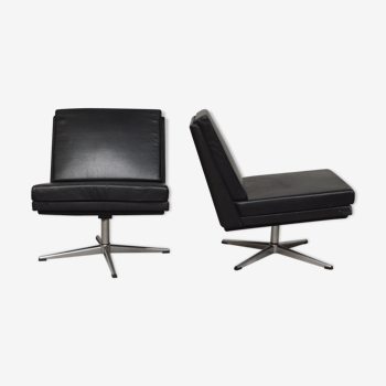 Pair of black leather armchairs warming cross feet