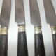 Set of 11 knives with black wooden handles.
