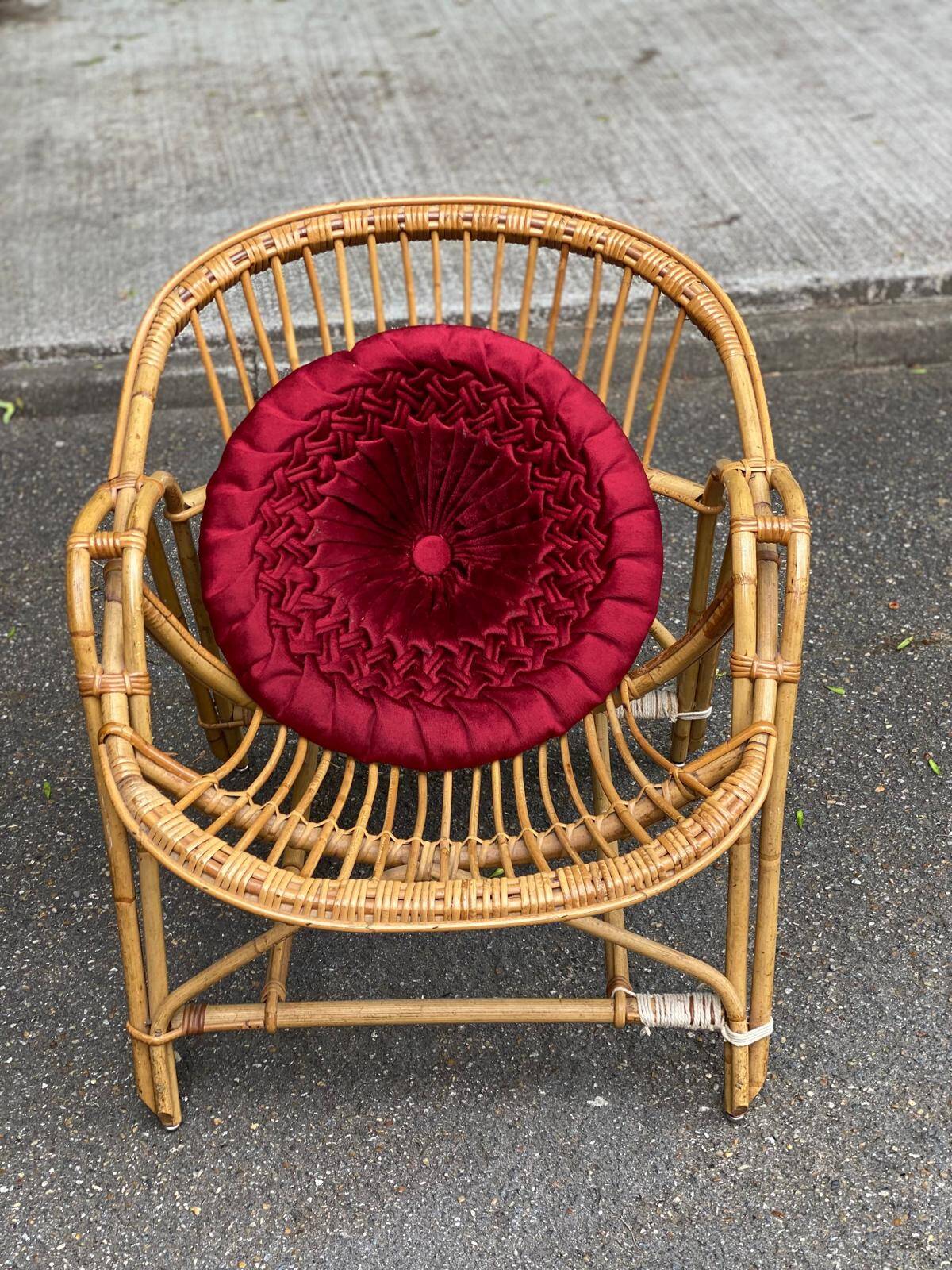 1970s adult rattan and wicker armchair with a round burgundy velvet cushion.