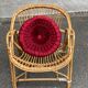 1970s adult rattan and wicker armchair with a round burgundy velvet cushion.