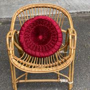 1970s adult rattan and wicker armchair with a round burgundy velvet cushion.