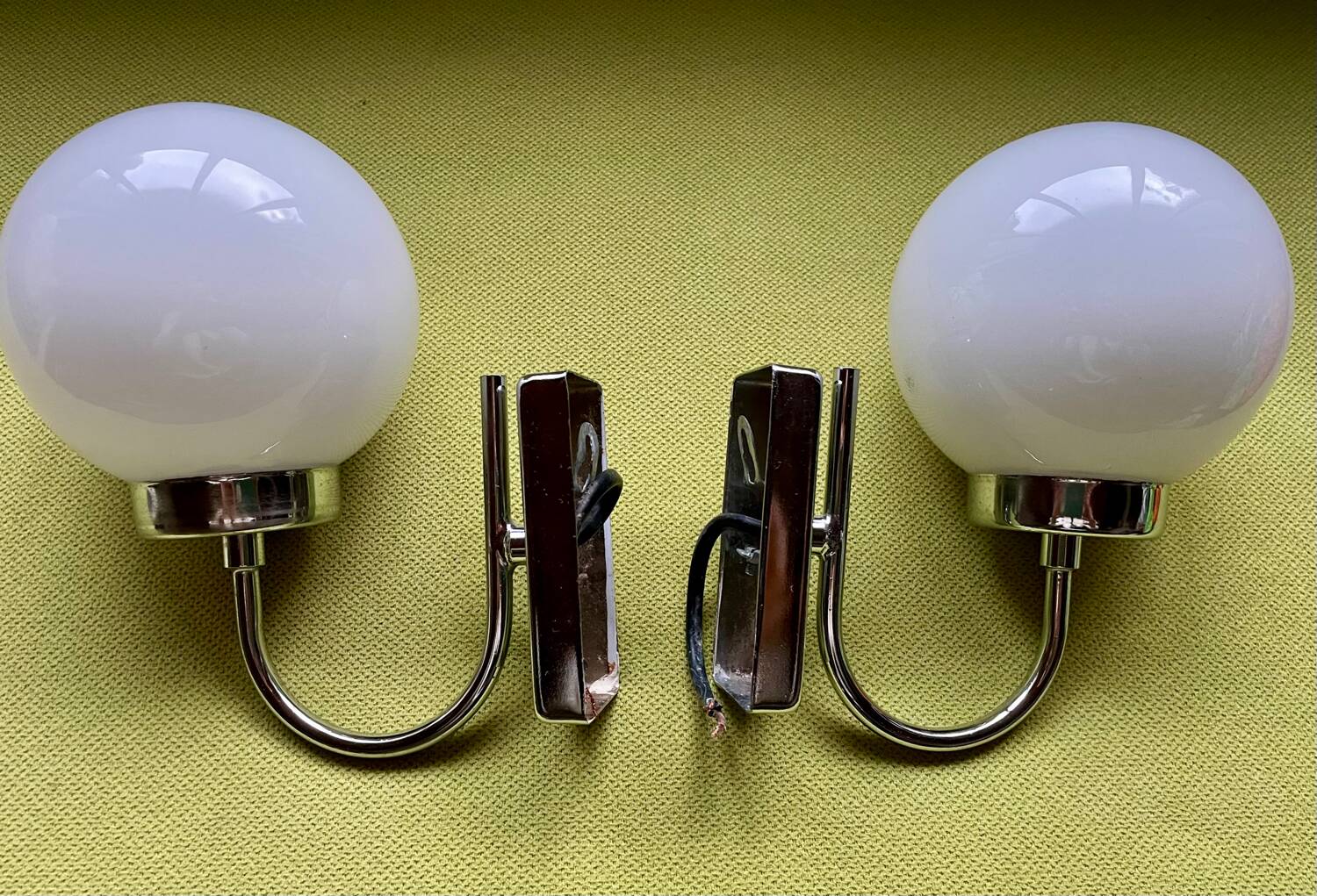 Pair of chrome metal wall lights with white glass globe.