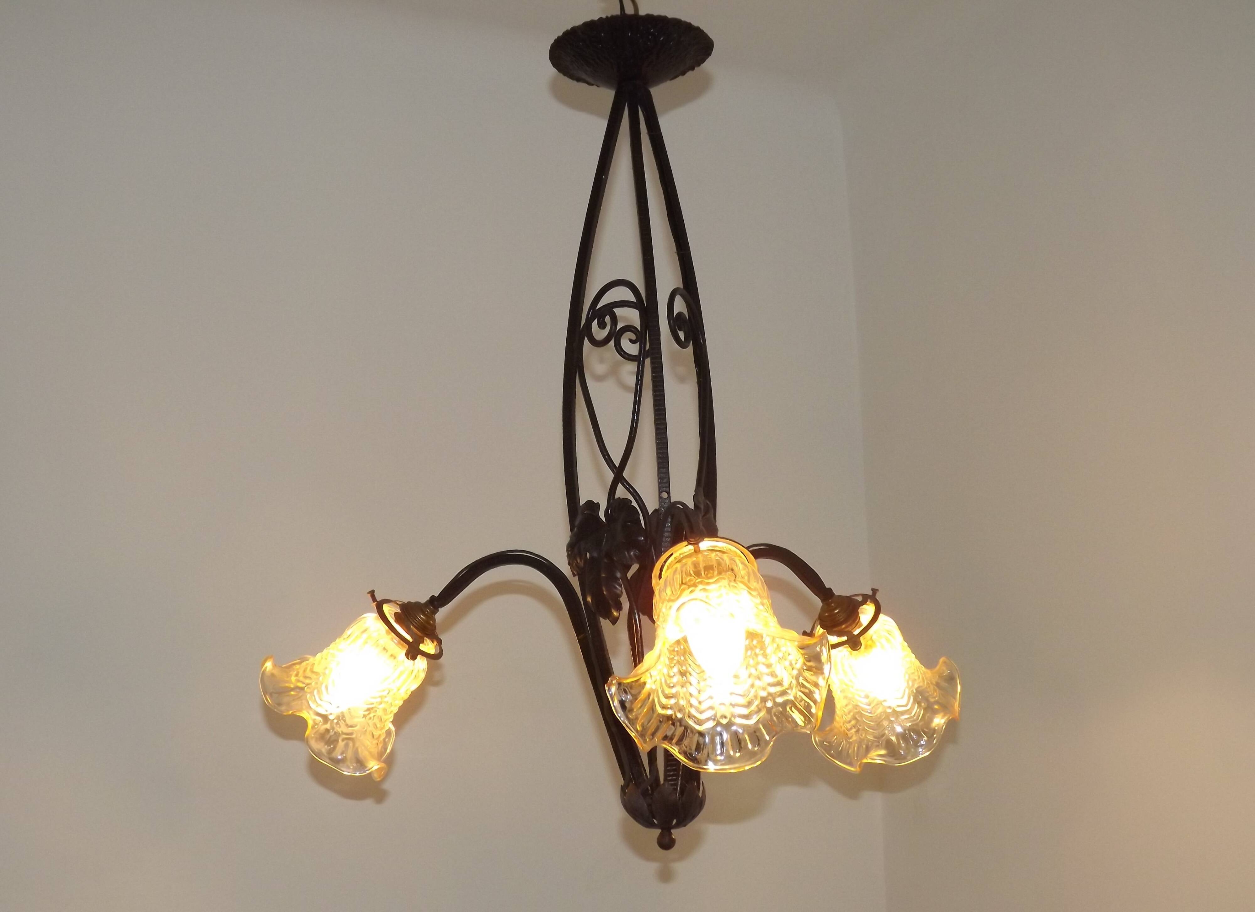 French Art Nouveau leaf detail iron three-light chandelier with amber glass shades.