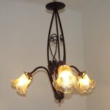 French Art Nouveau leaf detail iron three-light chandelier with amber glass shades.