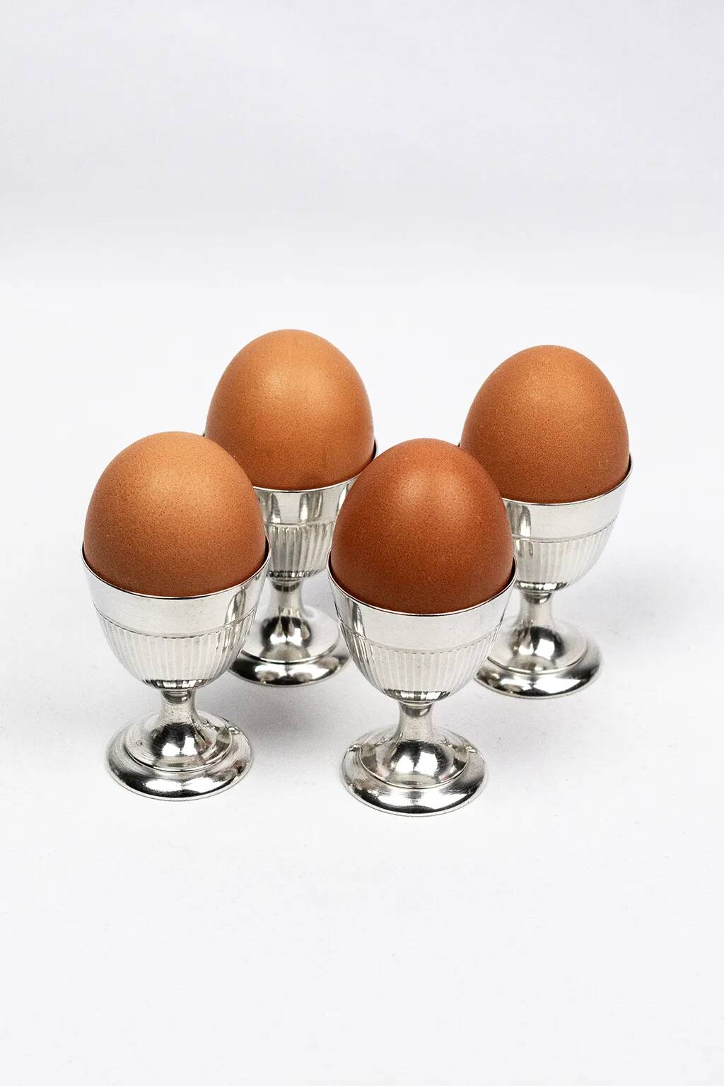 Four silver-plated Christofle egg cups with fluted sides.