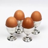 Four silver-plated Christofle egg cups with fluted sides.