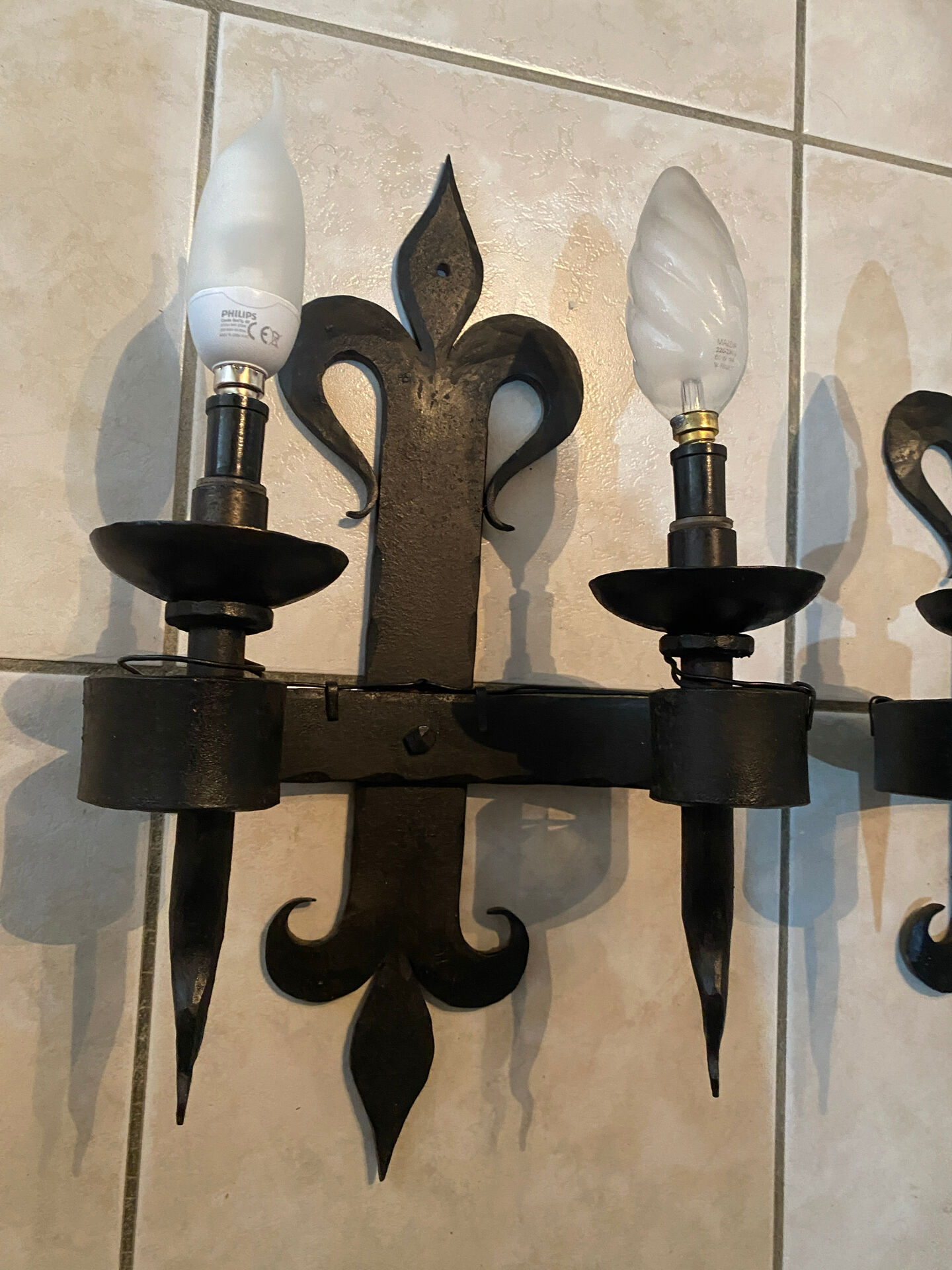 Pair of wrought iron wall lights in fleur-de-lis château style.