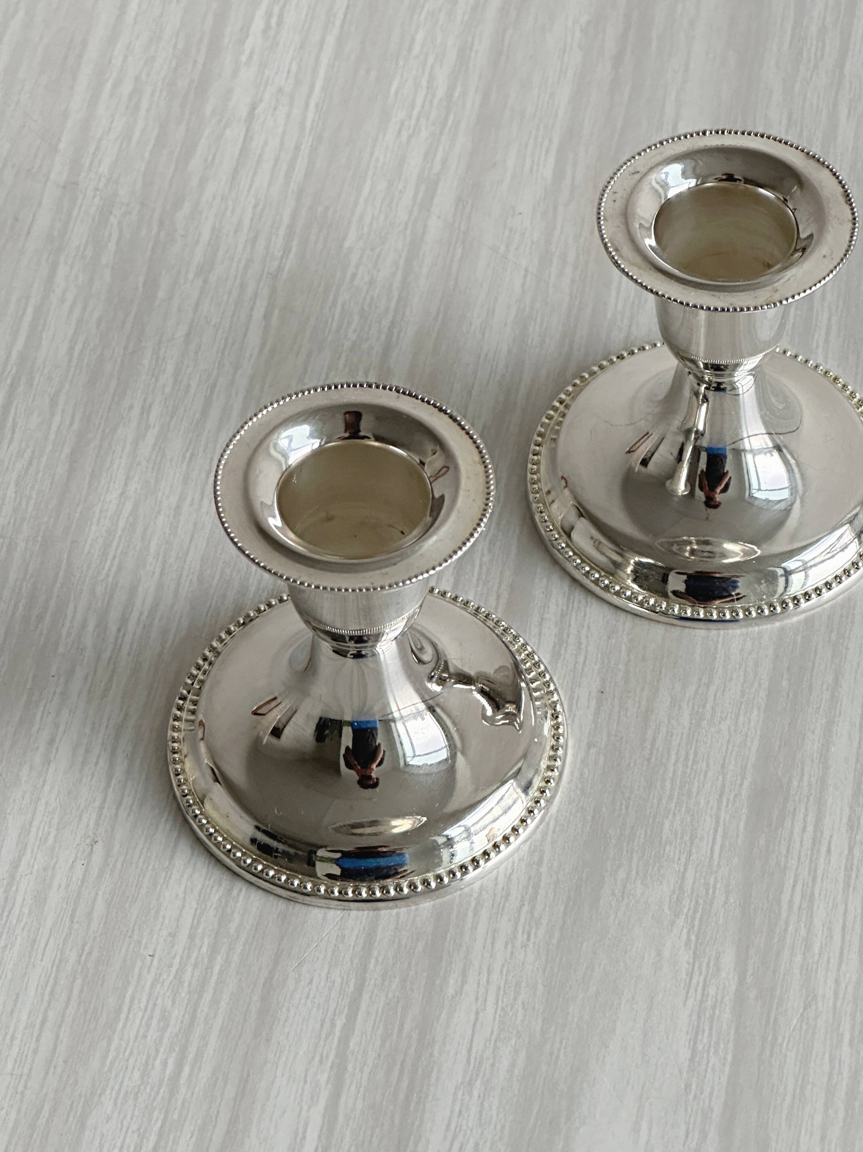 A pair of small silver-white metal candle holders.