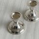 A pair of small silver-white metal candle holders.