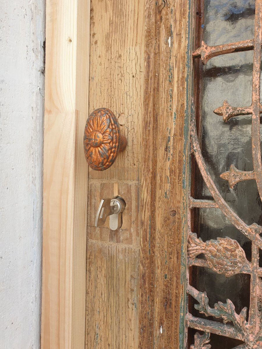 Front door of a house or building in the city centre, with a dolphin door knocker and frame + transom.