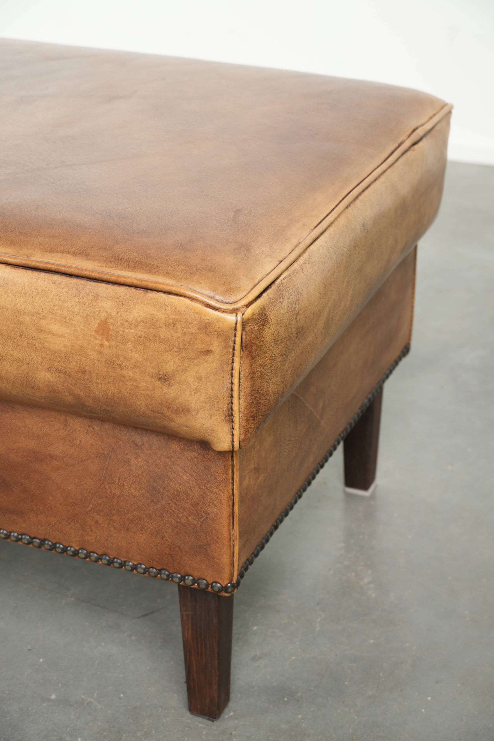 Cowhide ottoman with a beautiful patina finished with decorative nails