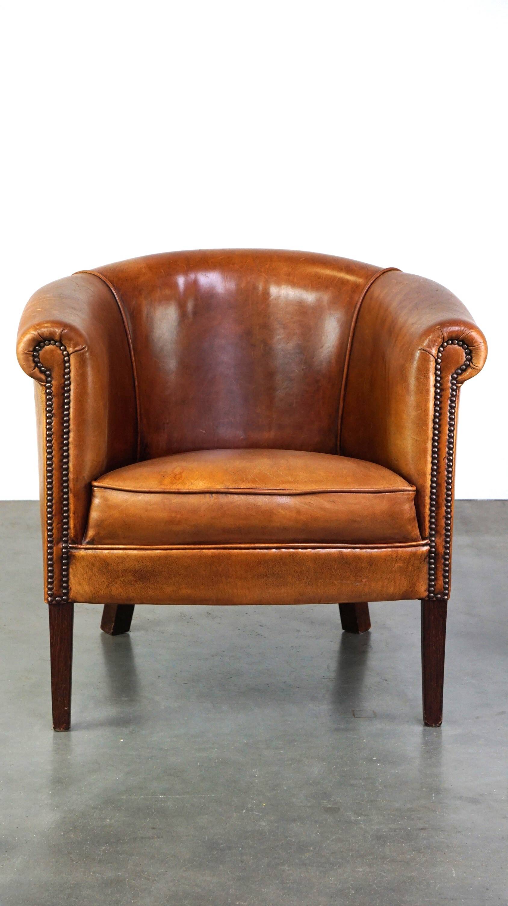 Neat and subtle sheepskin club chair, finished with decorative studs and a fixed seat cushion