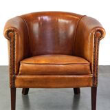 Neat and subtle sheepskin club chair, finished with decorative studs and a fixed seat cushion