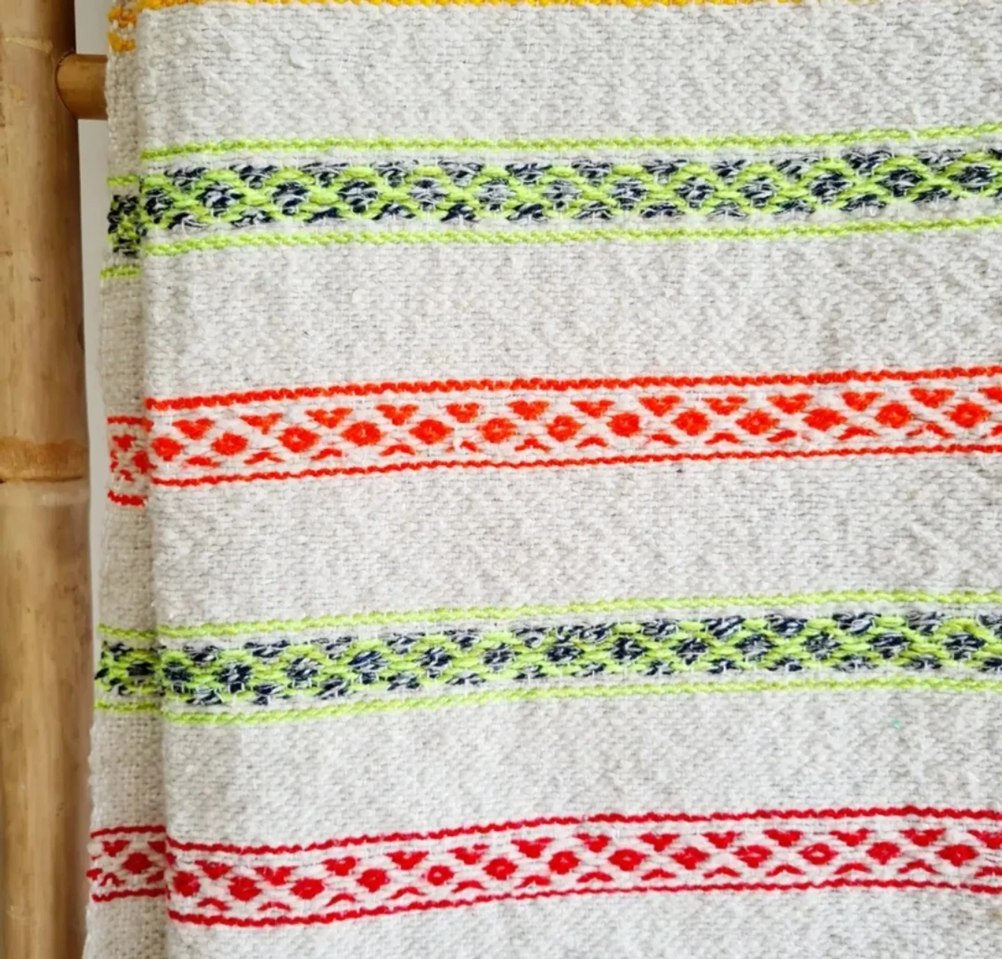 Moroccan plaid made of handwoven wool, decorated with stripes and pom-poms.
