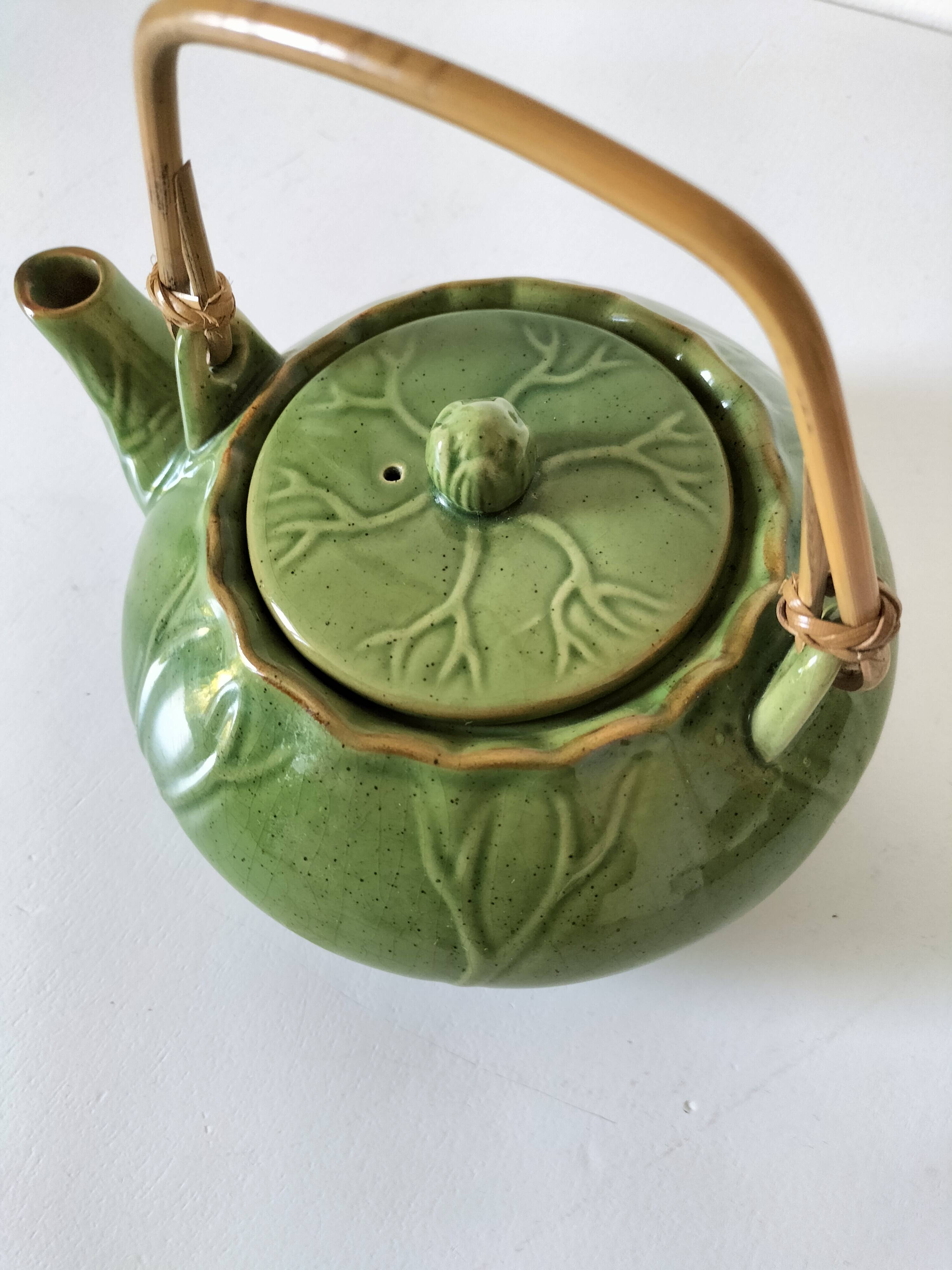 Vintage green teapot with lotus decoration and bamboo handle.